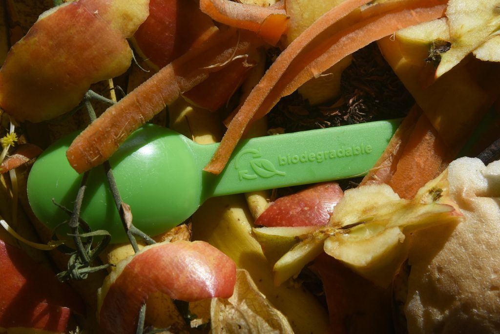 grüner Bioplastiklöffel im Kompost